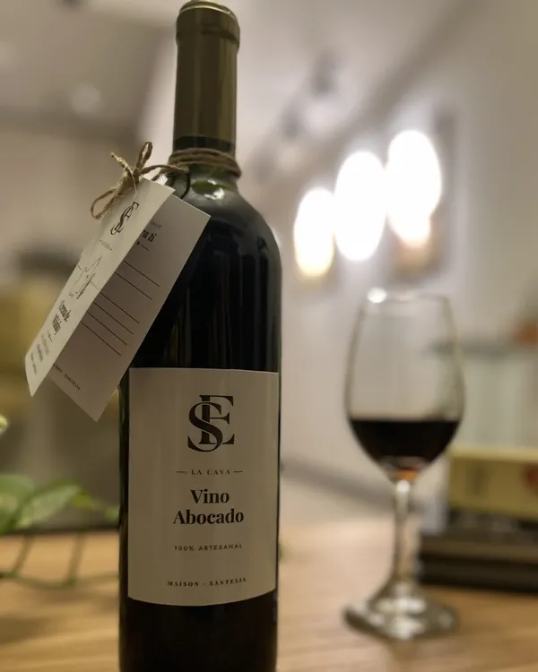 Botella de Vino abocado de La Cava, con etiqueta del monograma SE, cordel y tarjeta, junto a una copa.